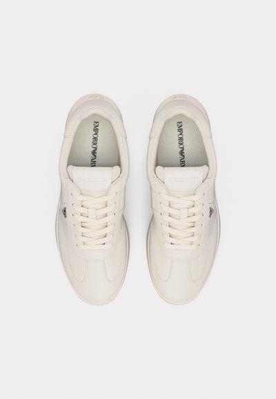 Ζευγάρι καθαρά λευκά αθλητικά παπούτσια Emporio Armani, φωτογραφημένα από πάνω, με δεμένα κορδόνια και ορατό το λογότυπο της μάρκας στο εσωτερικό.