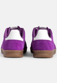 Sneakers in suede viola con dettagli in bianco, dotati di un tallone texturizzato e una suola in gomma. La vista posteriore mostra il colletto imbottito e il tassello per la presa.