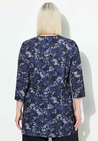 Bloemachtige tuniek met driekwartmouwen, met een donker marineblauwe achtergrond en lichtblauwe bloemenpatronen. Gladde stof en losse pasvorm.