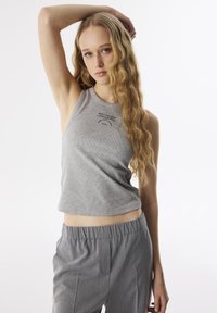 Top in cotone grigio a coste con scollatura rotonda e orlo corto, con un motivo stampato nella zona del petto. Abbinato a pantaloni grigi con vita elastica.