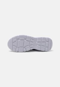 White sneaker sole with textured rubber surface, featuring deep grooves and patterns for traction. Rounded toe, flat heel for stability.