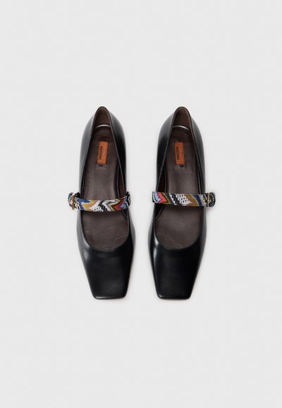 Black leather heels with a square toe and a colorful patterned strap. Smooth texture with a cushioned insole for comfort.