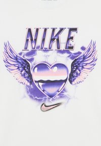 Baltas marškinėlis su violetinės ir rožinės spalvų širdies su sparnais grafika, viršuje užrašas „NIKE“, apačioje Nike logotipas.