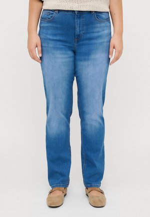 Light blue denim jeans with a straight cut, five pockets, and subtle fading on the thighs. Paired with beige flats.