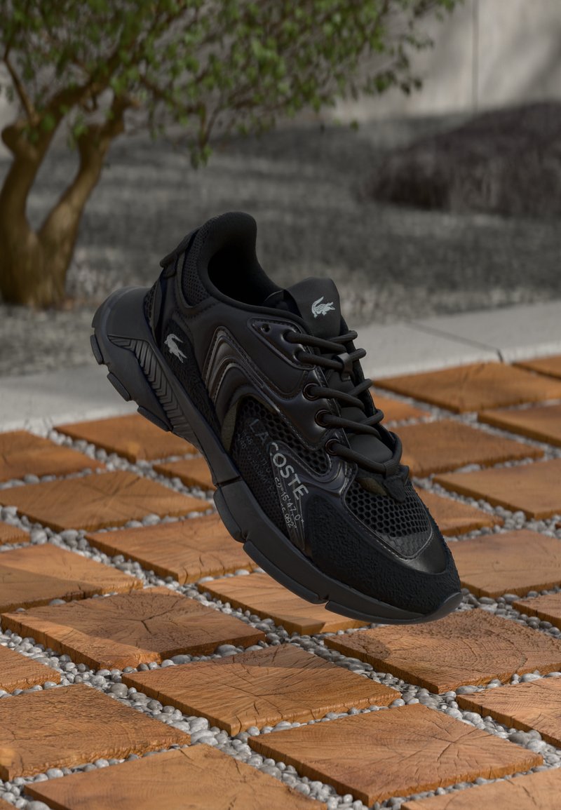 Baskets de sport noires avec un dessus en mesh, des accents texturés et un col rembourré. La semelle intermédiaire présente un design épuré avec une semelle extérieure en caoutchouc.