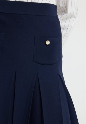 Marineblauer Faltenrock aus strukturiertem Stoff, mit einem breiten Taillenbund, zwei Fronttaschen und goldenen Akzentknöpfen.