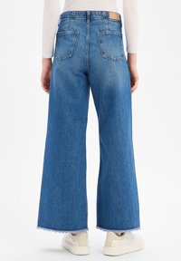 Weit geschnittene blaue Jeans mit ausgefranstem Saum, aus Denim gefertigt. Verfügt über zwei Gesäßtaschen und ein Markenlabel am Taillenbund.