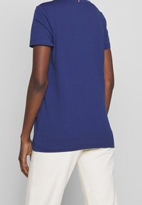 Námořnická modrá bavlněná tričko s krátkým rukávem a kulatým výstřihem, s rovným lemem a minimálními švy.