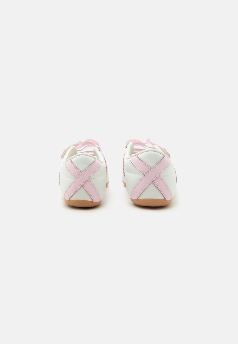 Een paar witte en roze babyschoentjes met roze X-vormige stiksels op de hielen, zachte zolen en bandjes over de bovenkant, geplaatst op een witte achtergrond.