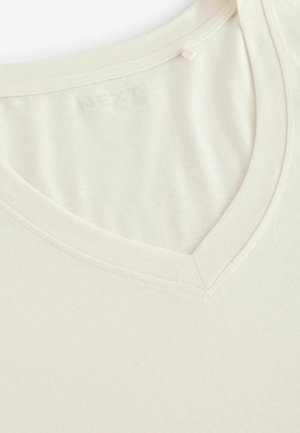 Majica kratkih rukava s v-izrezom u boji off-white, izrađena od mekog materijala s glatkom teksturom; sadrži suptilan logo blizu izreza.