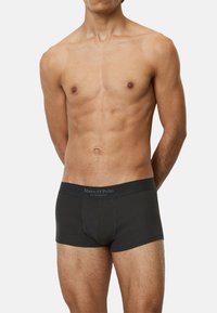 Schwarze Boxershorts für Männer mit geripptem Material, ausgestattet mit einem breiten Bund, der mit "Marc O'Polo" beschriftet ist. Die Passform ist körperbetont und kurz.