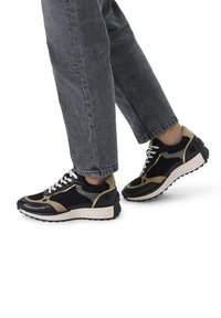 Zwart-gouden sneakers van leer en suède, met een ronde neus, gestructureerde zolen en contrasterende accenten aan de zijkanten.