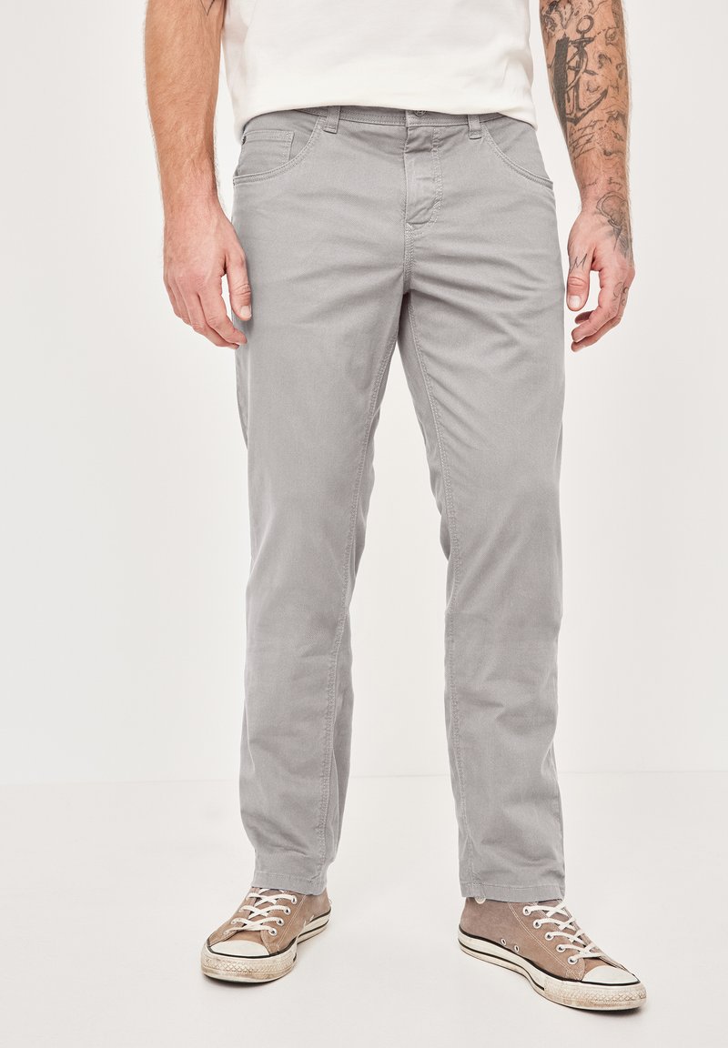 Gray cotton trousers with a slim fit, featuring two front pockets and a button closure. Paired with beige canvas sneakers.