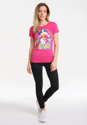 Pink cotton t-shirt featuring a Wonder Woman graphic with stars. Paired with black skinny jeans and white sneakers.