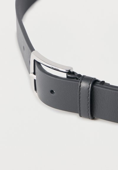 Μαύρη δερμάτινη ζώνη με ασημένια ορθογώνια πόρπη, μία θηλιά ζώνης και μία ορατή τρύπα ρύθμισης σε λευκό φόντο.