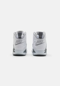 Valged ja hallid Nike jalatsid, millel on pehme kaelus, tekstuuriga kanga ja silmapaistev logo kontsapoolses osas. Ümar disain toetava tallaga.