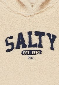 Beige fleece hoodie met een gestructureerd oppervlak. Heeft navy blauwe geborduurde tekst: "SALT" en "EST. 1990" op de borst.