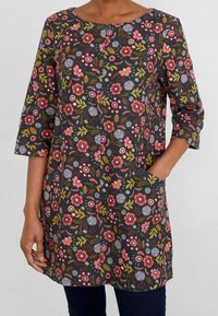 Blommig tunika med rundad halsringning, trekvartslånga ärmar och fickor. Har en mörk bakgrund med rosa, lila och gröna mönster.