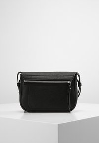 Černá kožená crossbody taška s texturovaným povrchem, přední kapsou na zip a ramenním popruhem, s minimalistickým designem a obdélníkovým tvarem.