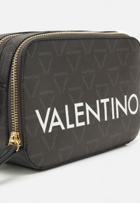 Borsa in pelle nera con motivo a logo ripetuto, hardware della cerniera dorato e il testo bianco "VALENTINO" in evidenza su un lato.