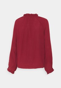 Blusa rossa a maniche lunghe con scollatura arricciata, maniche raglan e polsini arricciati. Tessuto liscio e leggero con una vestibilità comoda.