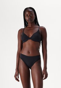 Conjunto de biquíni preto composto por um soutien com almofadas e alças ajustáveis, e parte de baixo de cintura baixa. Feito de material suave e leve com um discreto logótipo da marca.
