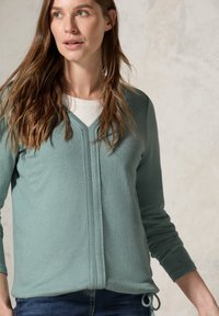 Helle türkisfarbene Strickjacke aus weichem Stoff, mit V-Ausschnitt, langen Ärmeln und einem gebundenen Detail am Saum; minimalistisches Design.