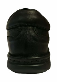 Zapato de cuero negro visto desde atrás, mostrando detalles de costura, un collar acolchado y suela gruesa sobre un fondo blanco.