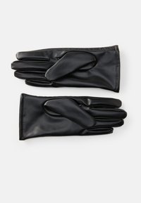 Un par de guantes de cuero negro extendidos, con detalle de costura en la muñeca y secciones separadas para cada dedo, sobre un fondo neutro.