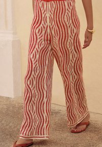 weite Hosen mit einem rot-weißen wellenförmigen Muster, hergestellt aus leichtem, glattem Stoff. Mit feinen Details versehen.