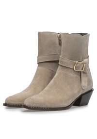 Bottes chukka en suède beige avec un bout effilé, une fermeture éclair sur le côté et un accent en boucle. Talon bas et incliné avec des coutures décoratives le long de la semelle.