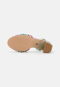Sandalo con tacco rosa dotato di una suola liscia, caratterizzato da cinturini metallici multicolori disposti in un motivo intrecciato sulla parte superiore.