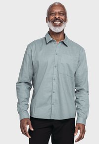 Helles blaue Langarmshirt mit durchgehender Knopfleiste, Brusttasche und dezentem Muster. Es hat einen Kragen und ein kleines Logo auf der Brust.