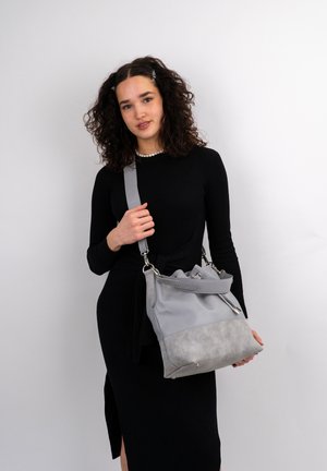 Bolso de mano gris con una sección superior lisa y una sección inferior texturizada. Presenta un cierre de cordón y detalles de hardware en plata.