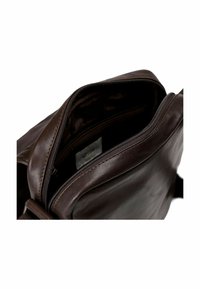 Bolso de cuero marrón con una abertura con cremallera, que muestra bolsillos interiores y una textura suave. Detalles de costura resistente a lo largo de las costuras.