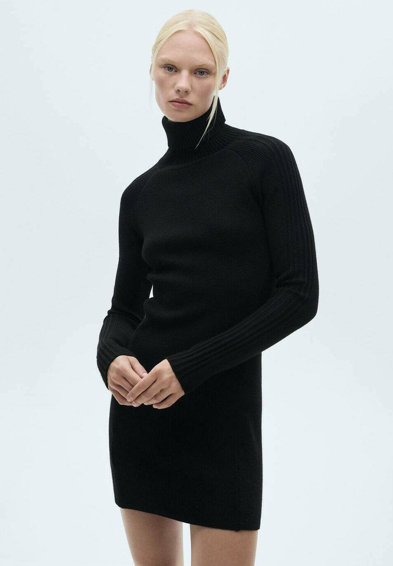 Črno rebrasto pleteno obleko z visokim turtleneck ovratnikom, dolgimi rokavi in prilegajočim silhueto. Ima navpične rebra na rokavih za teksturo.