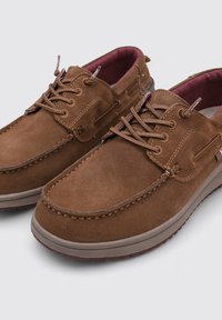 Scarpe in suede marrone con punta arrotondata, cuciture dettagliate e design con lacci. L'interno presenta una fodera bordeaux. Suola in gomma per una buona aderenza.
