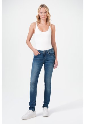 Lichtblauwe rekbare jeans, aansluitend ontwerp met vijfzakkenstijl, gecombineerd met een aansluitend wit tanktop en witte sneakers.