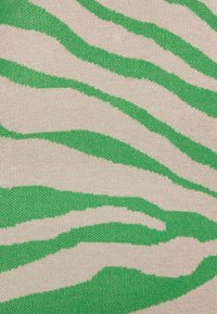 Tissu présentant un fond beige avec des rayures de zèbre vertes. Le motif est tricoté avec une finition texturée, affichant un motif contrasté.