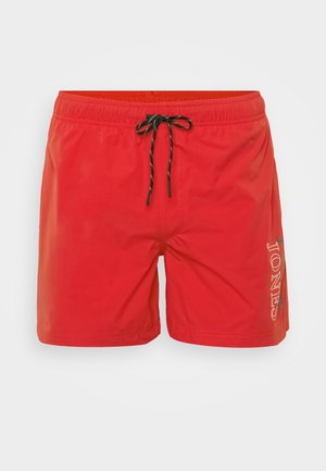 Shorts de bain rouges en matériau léger et à séchage rapide. Dotés d'une taille élastique avec cordon de serrage noir et d'un logo blanc sur le côté.