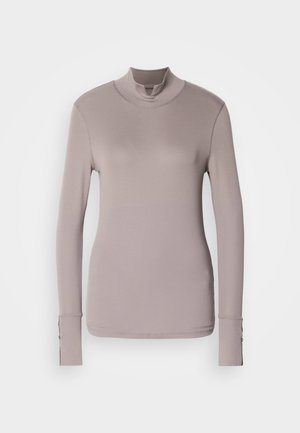 Lange mouwen turtleneck top in licht mauve, gladde textuur, aansluitend design, met knoopaccenten op de manchetten, minimalistische stijl.