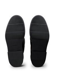 Suelas negras de goma Calvin Klein con diversas ranuras horizontales y verticales, con un acabado liso y mate y una marca sutil.