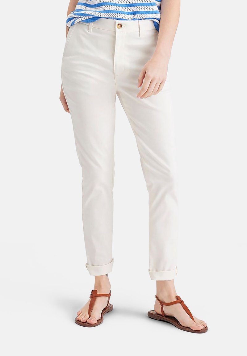 Vita bomullbyxor med rak passform, upprullade benslut och knappstängning. Kompletterade med bruna flip-flops.