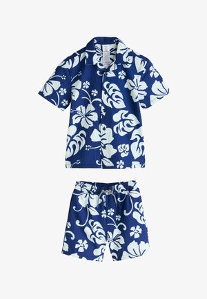 Marineblaues kurzärmeliges Hemd und passende Shorts mit weißen Blumenmustern. Das Hemd hat einen Kragen und Knöpfe; die Shorts haben einen elastischen Bund.