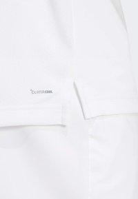 White athletic shirt featuring perforated fabric for breathability, with a side slit and "CLIMACOOL" branding near the hem.