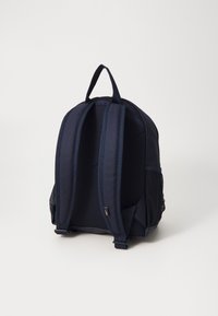 Sac à dos bleu marine avec des bretelles rembourrées, des poches latérales en maille et une poignée supérieure. Il présente un design structuré et un tissu durable.