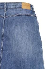 Achteraanzicht van blauwe denim jeans met een leren label waarop 'PULZ JEANS' bij de tailleband staat.