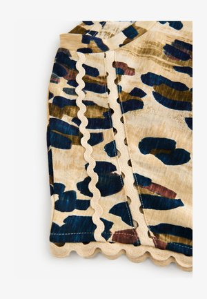 Meerleurige blouse met beige stof en abstracte patronen in donkerblauw en groen. Geschulpte randen langs de naden zorgen voor extra detail.