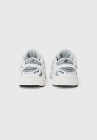 White and gray athletic shoes with mesh and synthetic materials, featuring a padded collar, textured sole, and branding on the heel.