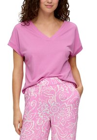 Roze V-hals T-shirt met korte mouwen, gecombineerd met lichtroze pantalon met een patroon van witte bloemen en een elastische tailleband.